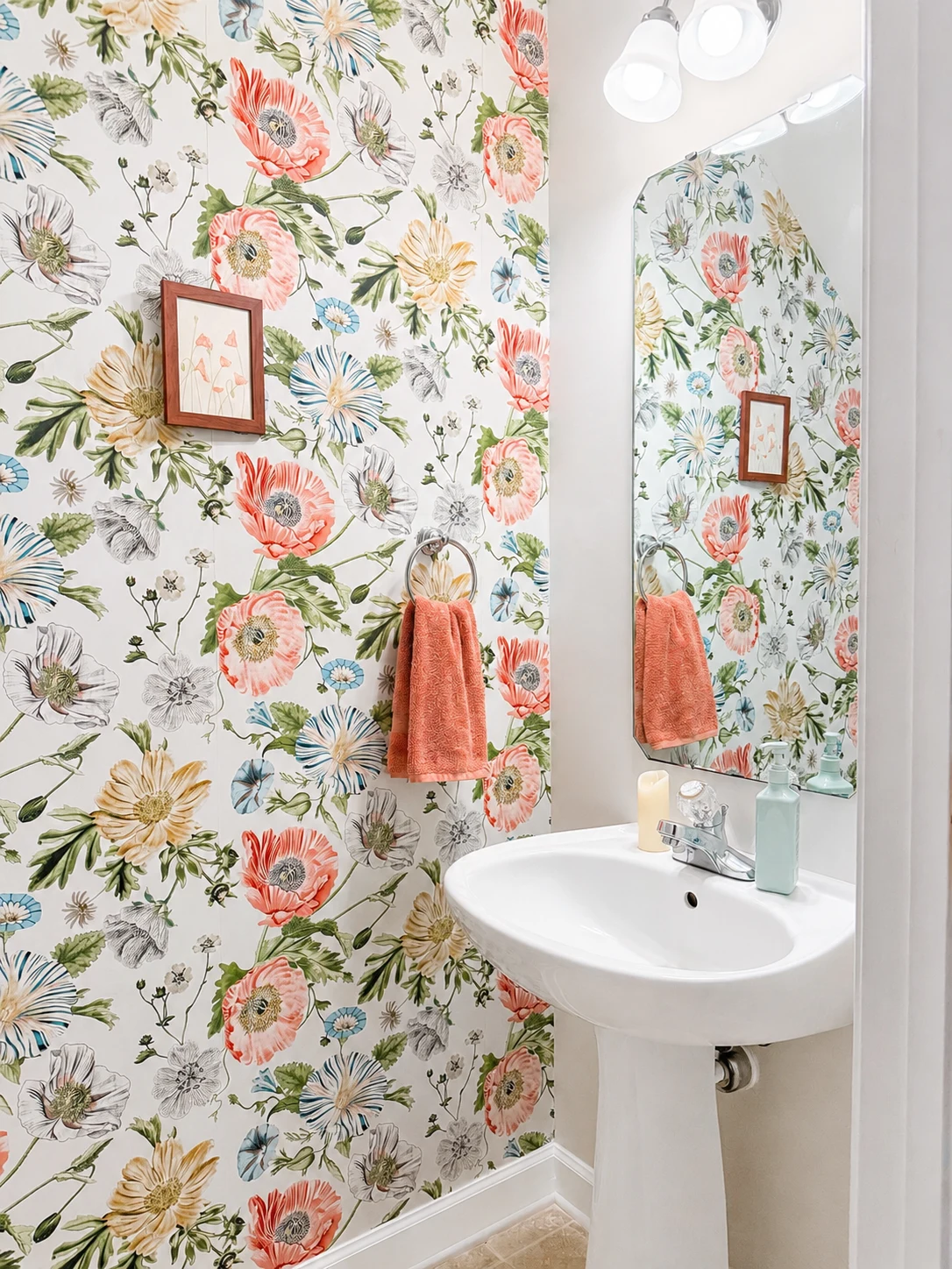 Bathroom with colourful botanical wallpaper, a pedestal sink, and coral hand towel