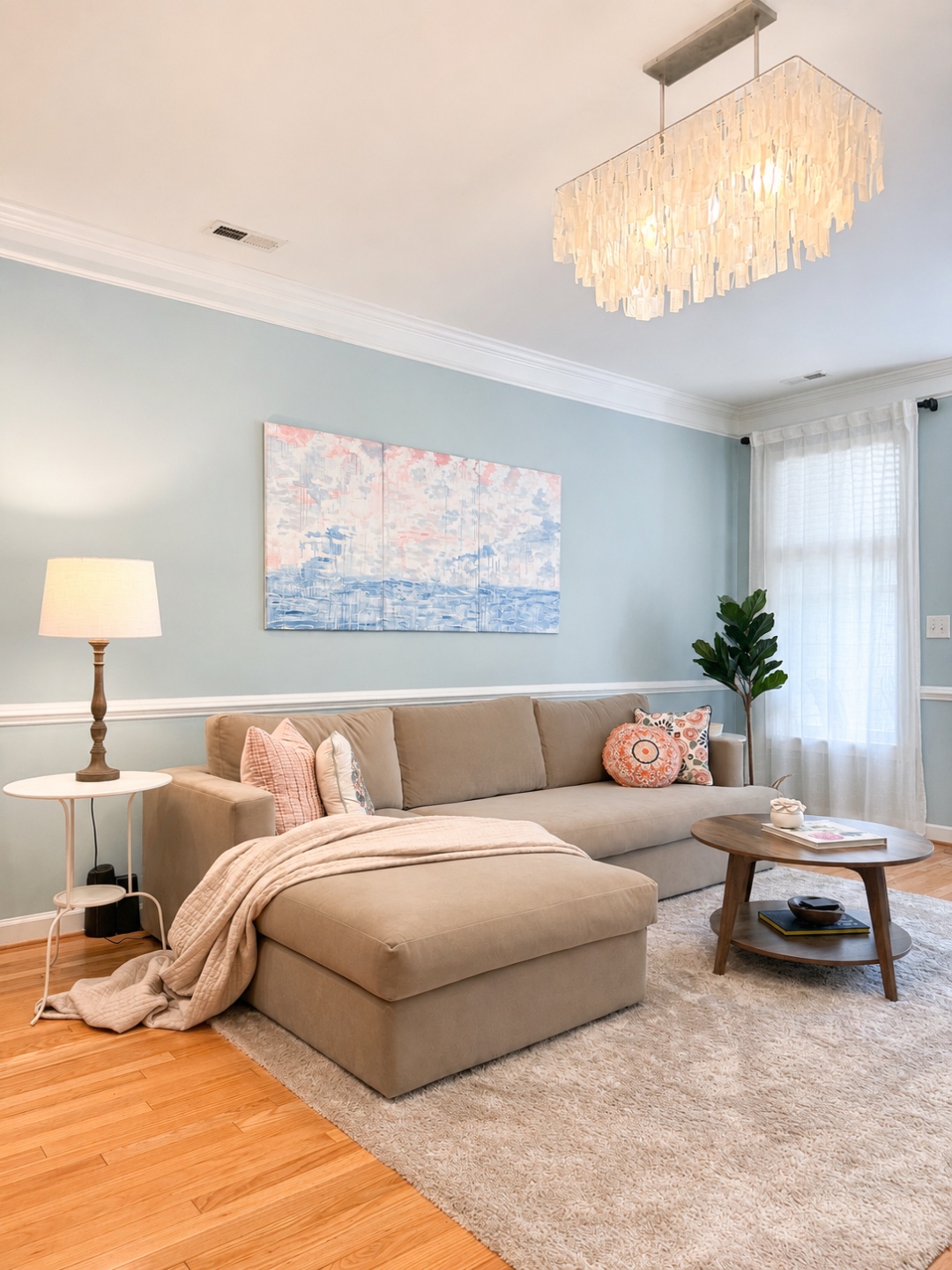 Sitting room with sectional, cloud triptych, and capiz chandelier