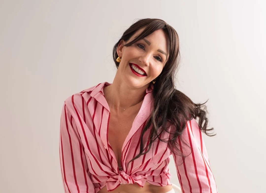 April Kensington smiling in a pink striped blouse