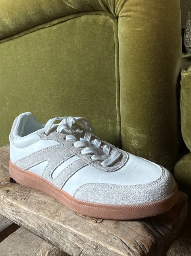 A white trainer styled on a green velvet chair