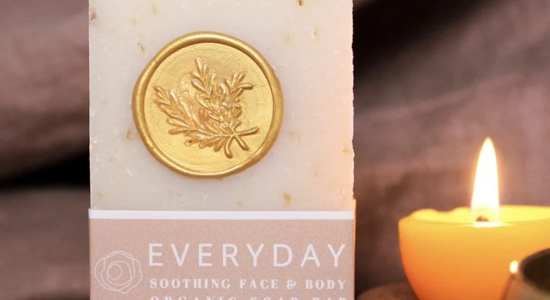 Product packaging with a gold seal beside candlelight